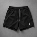Black athletic shorts with a white drawstring and a white Gothic-style 'L' logo on the lower left leg, laid flat on a textured gray background.